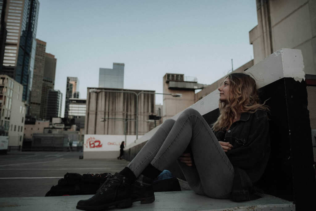 Jugendliche sitzt auf einer Dachterrasse und blickt über die Stadt